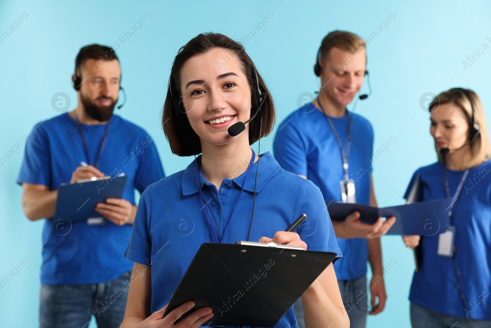 Photo of Technical support call center. Team of friendly operators working on light blue background