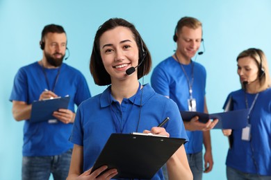 Photo of Technical support call center. Team of friendly operators working on light blue background