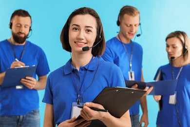 Photo of Technical support call center. Team of friendly operators working on light blue background