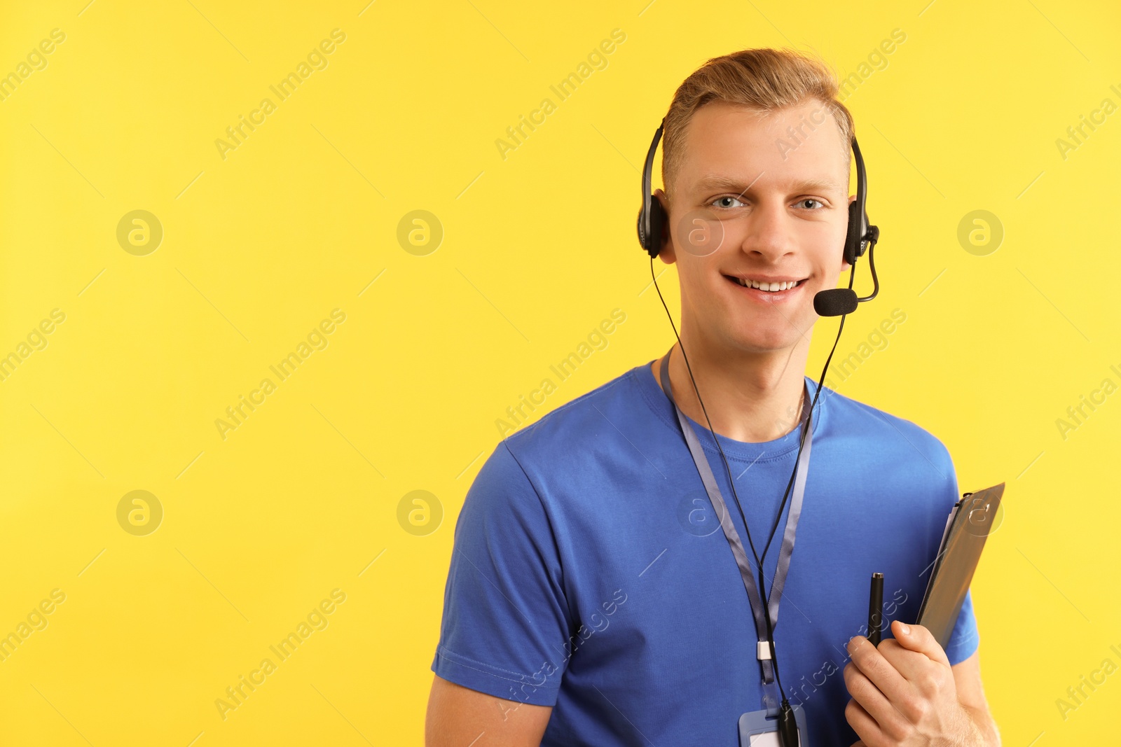 Photo of Technical support call center. Smiling operator with clipboard on yellow background. Space for text