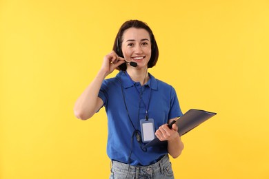 Photo of Technical support call center. Smiling operator with folder on yellow background