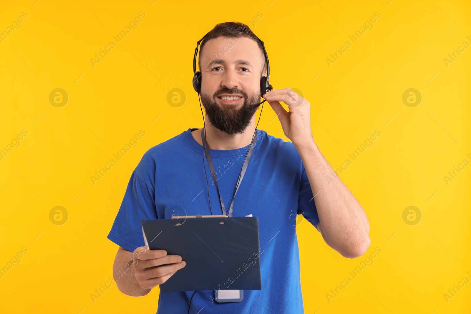 Photo of Technical support call center. Smiling operator with clipboard on yellow background