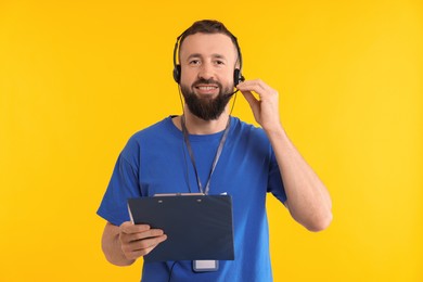 Photo of Technical support call center. Smiling operator with clipboard on yellow background