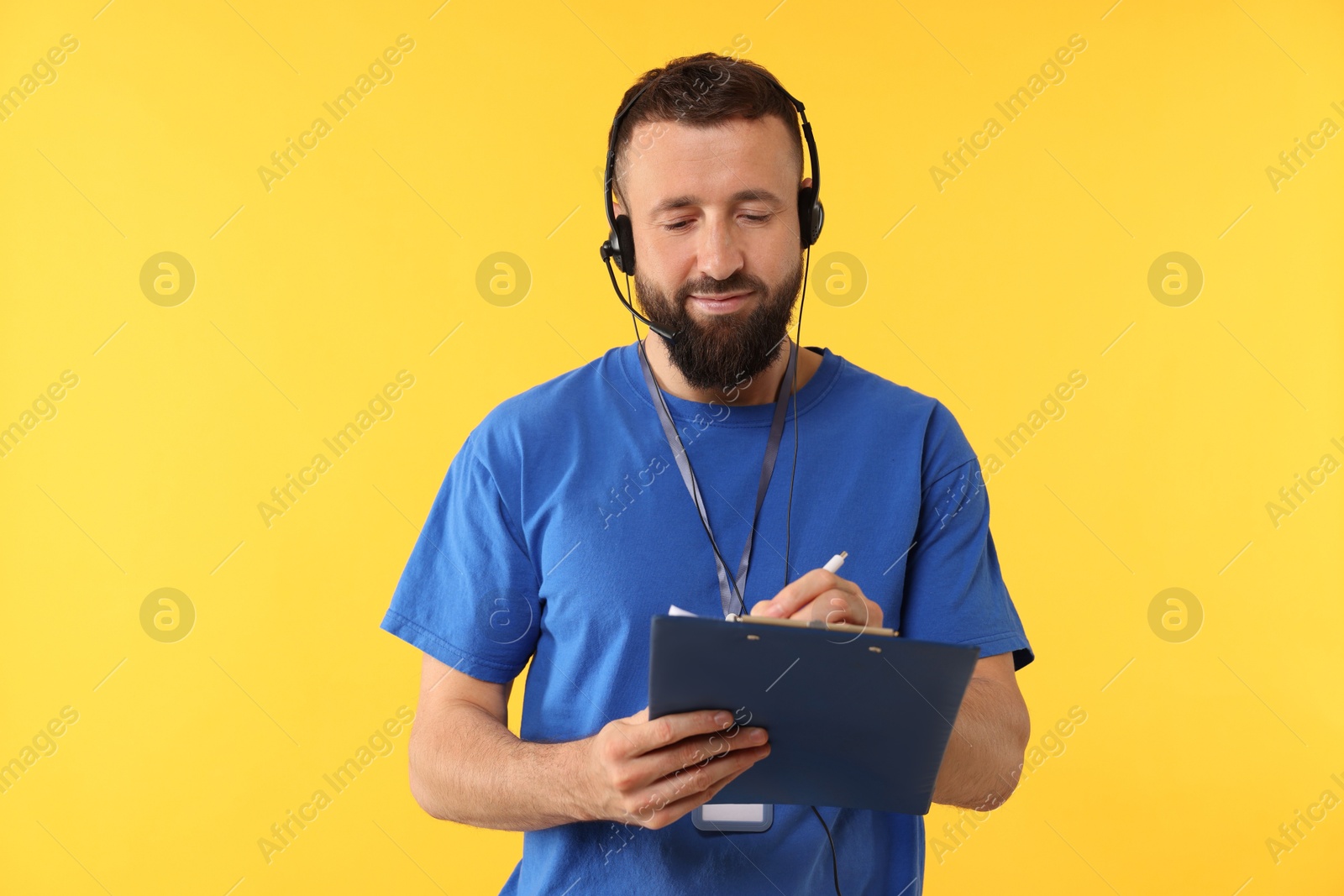 Photo of Technical support call center. Operator working with clipboard on yellow background