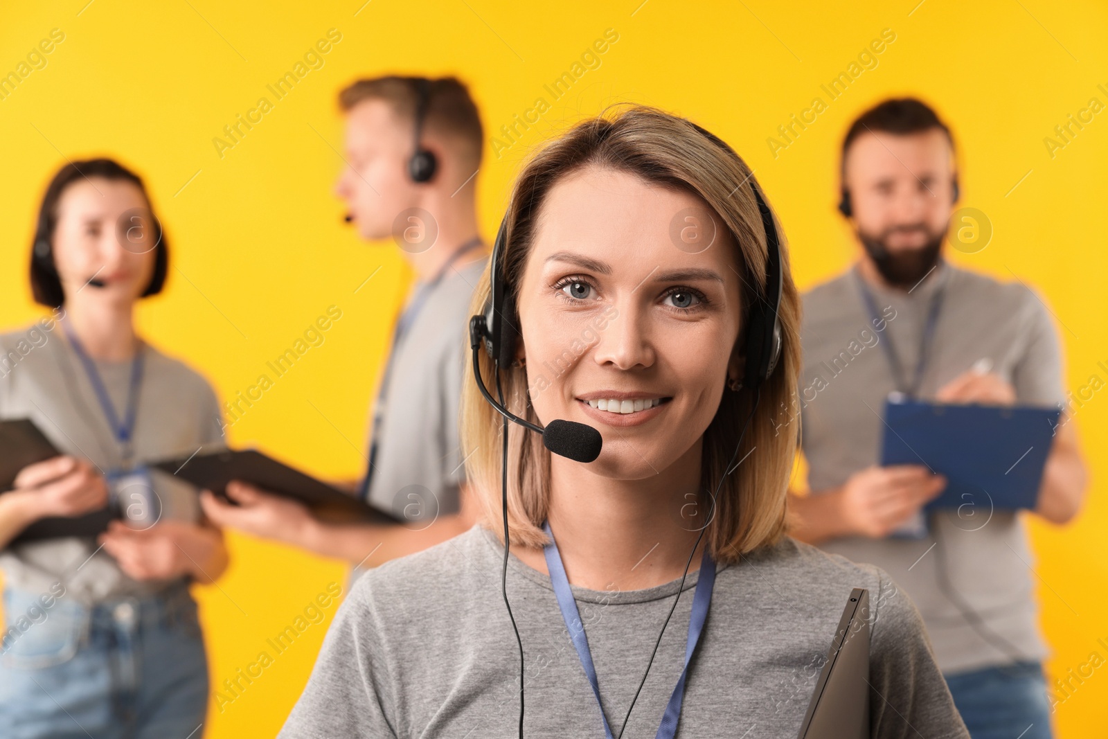 Photo of Technical support call center. Smiling operator on yellow background, selective focus