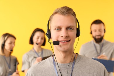 Photo of Technical support call center. Smiling operator on yellow background, selective focus