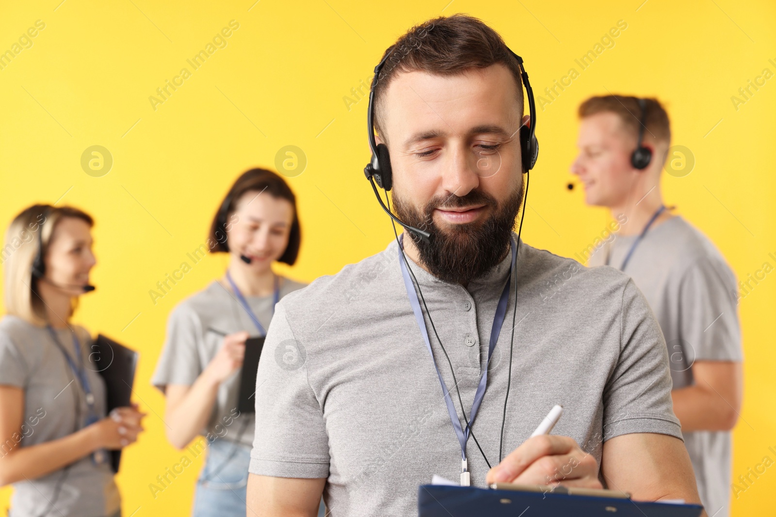 Photo of Technical support call center. Team of friendly operators on yellow background