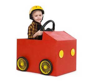 Little boy driving car made of cardboard on white background