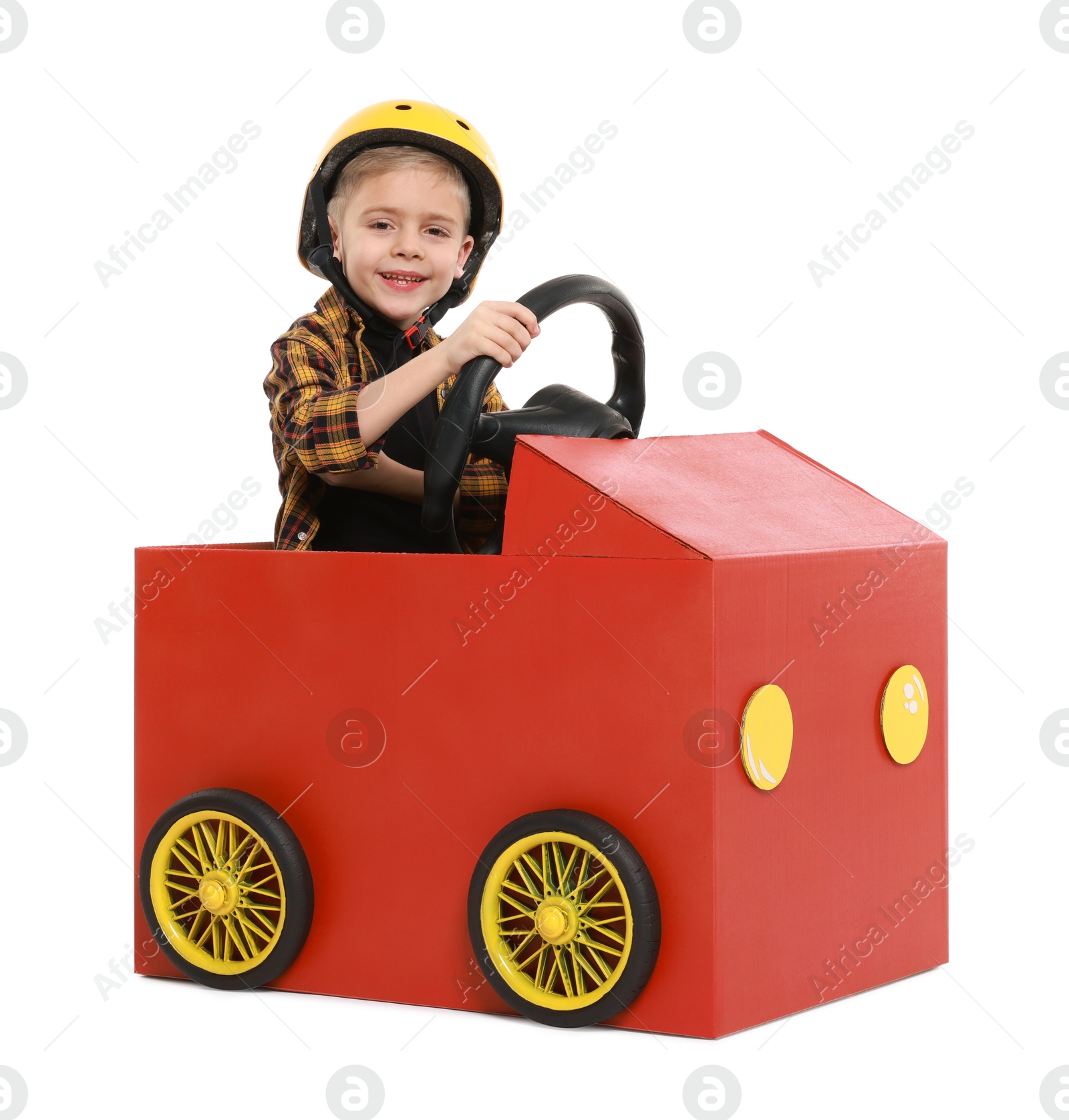 Photo of Little boy driving car made of cardboard on white background