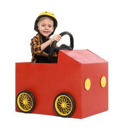 Photo of Little boy driving car made of cardboard on white background