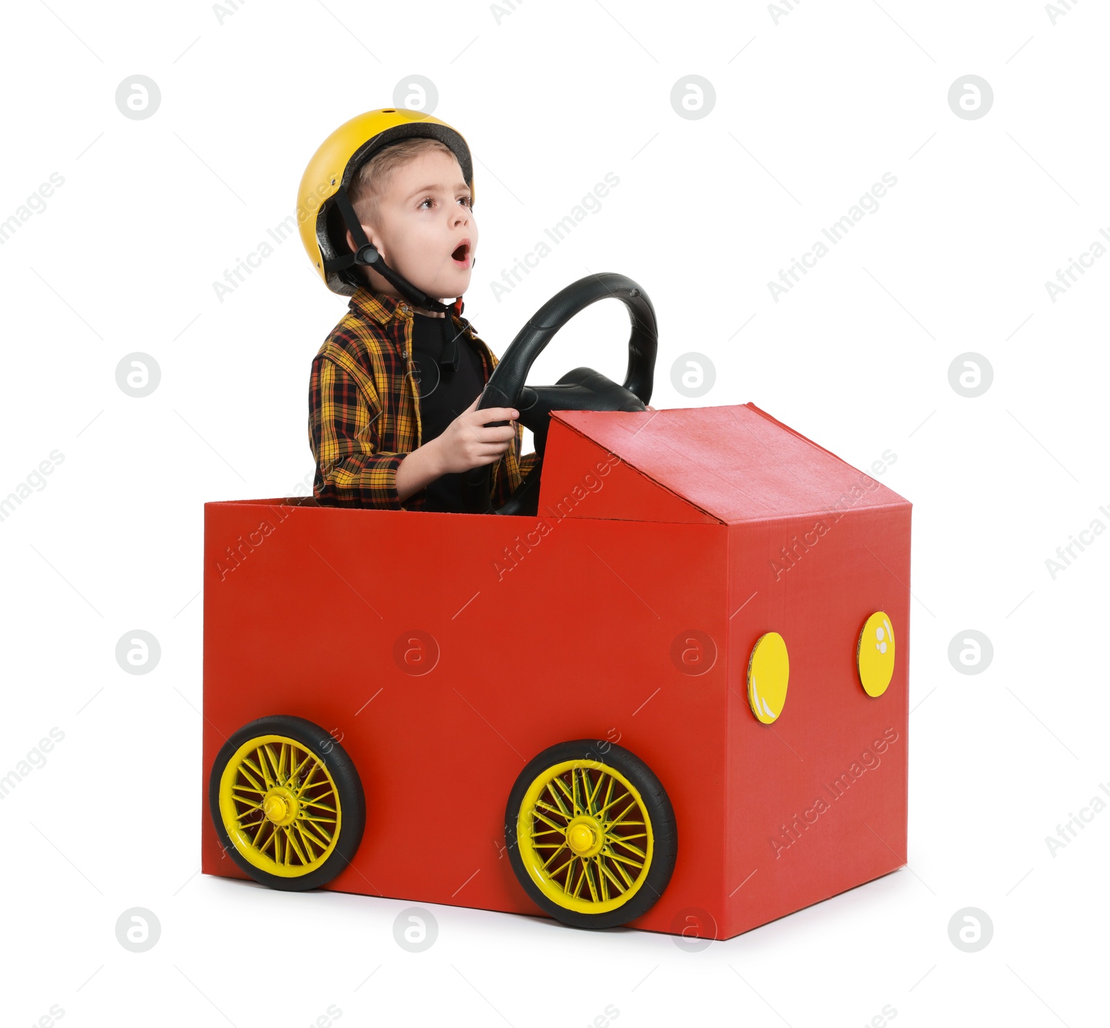 Photo of Surprised little boy driving car made of cardboard on white background