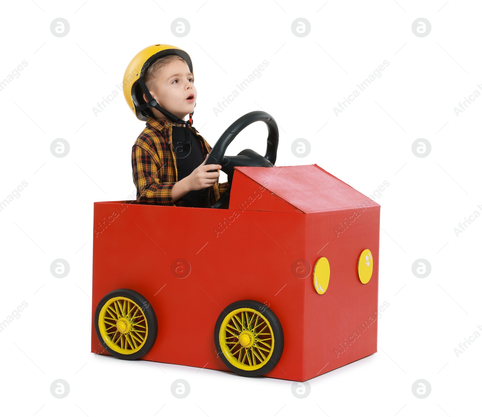 Photo of Surprised little boy driving car made of cardboard on white background