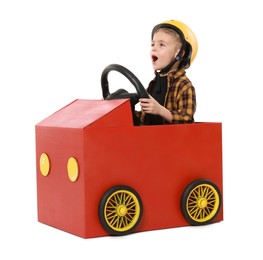 Photo of Surprised little boy driving car made of cardboard on white background