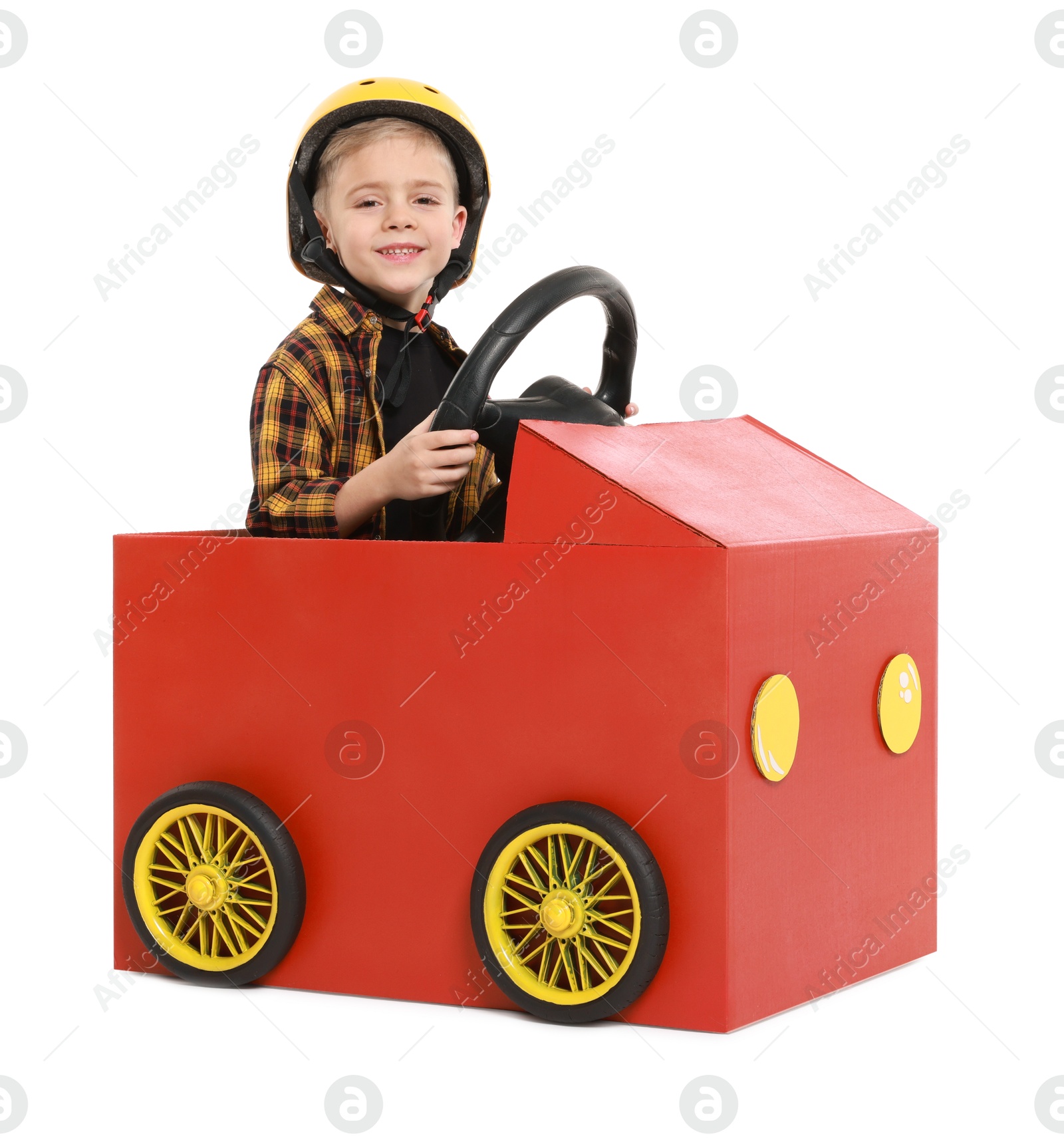 Photo of Little boy driving car made of cardboard on white background