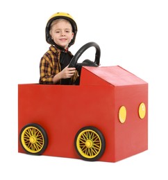 Photo of Little boy driving car made of cardboard on white background