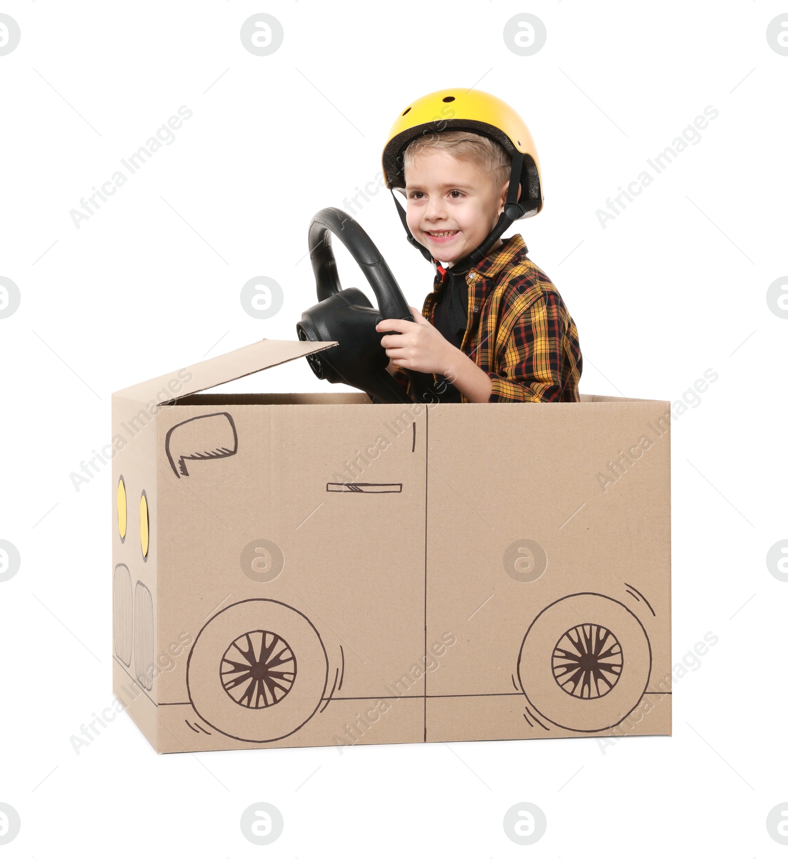 Photo of Little boy driving car made of cardboard on white background