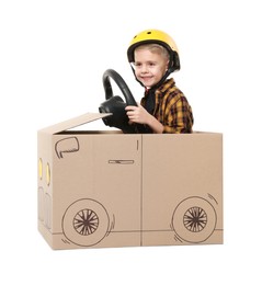 Little boy driving car made of cardboard on white background