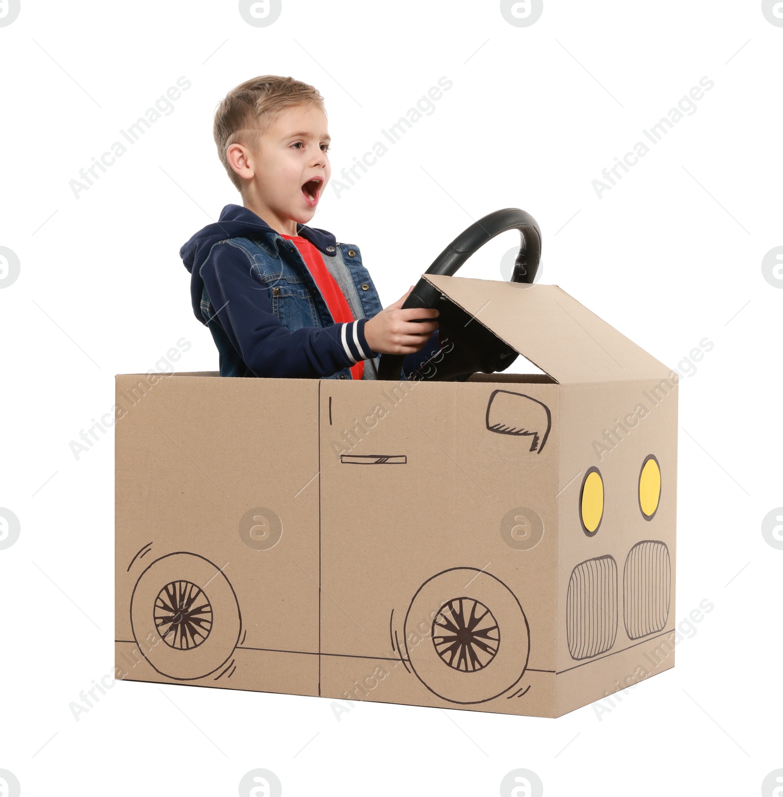 Photo of Little boy driving car made of cardboard on white background