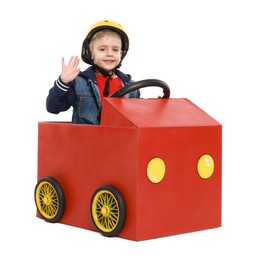 Little boy waving while driving car made of cardboard on white background