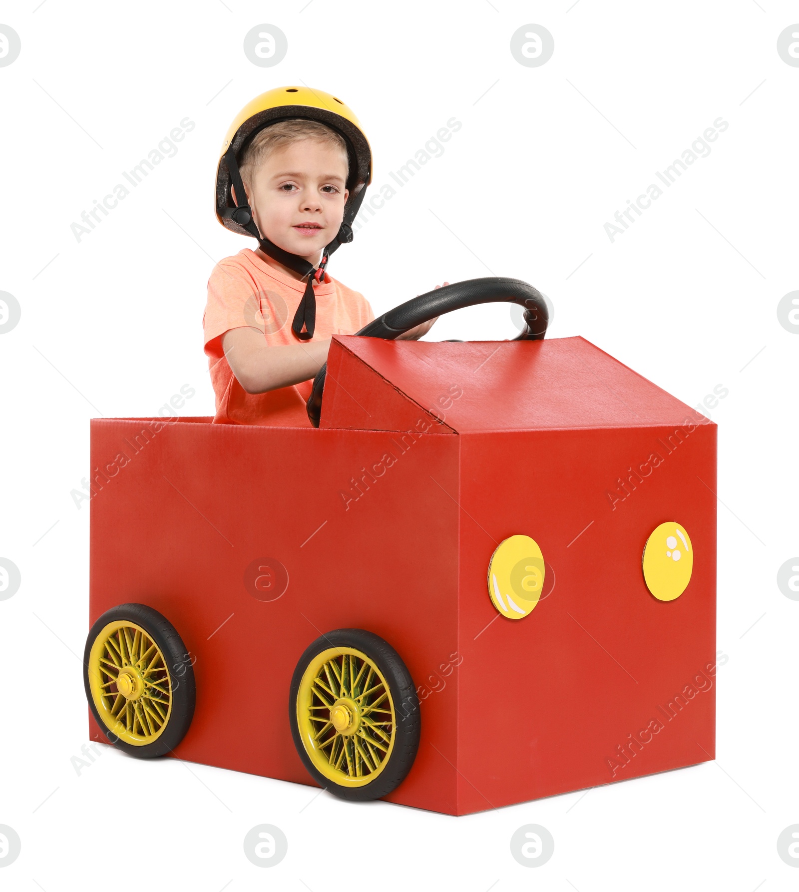 Photo of Little boy driving car made of cardboard on white background