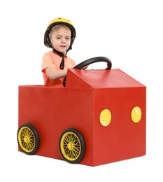 Little boy driving car made of cardboard on white background