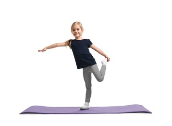 Little girl exercising on fitness mat against white background. Sport activity