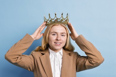 Smiling businesswoman in elegant crown on light blue background