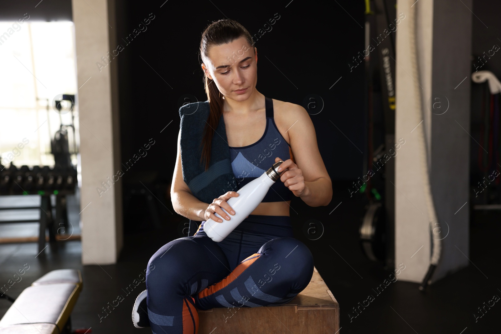 Photo of Happy woman with towel and water bottle in gym