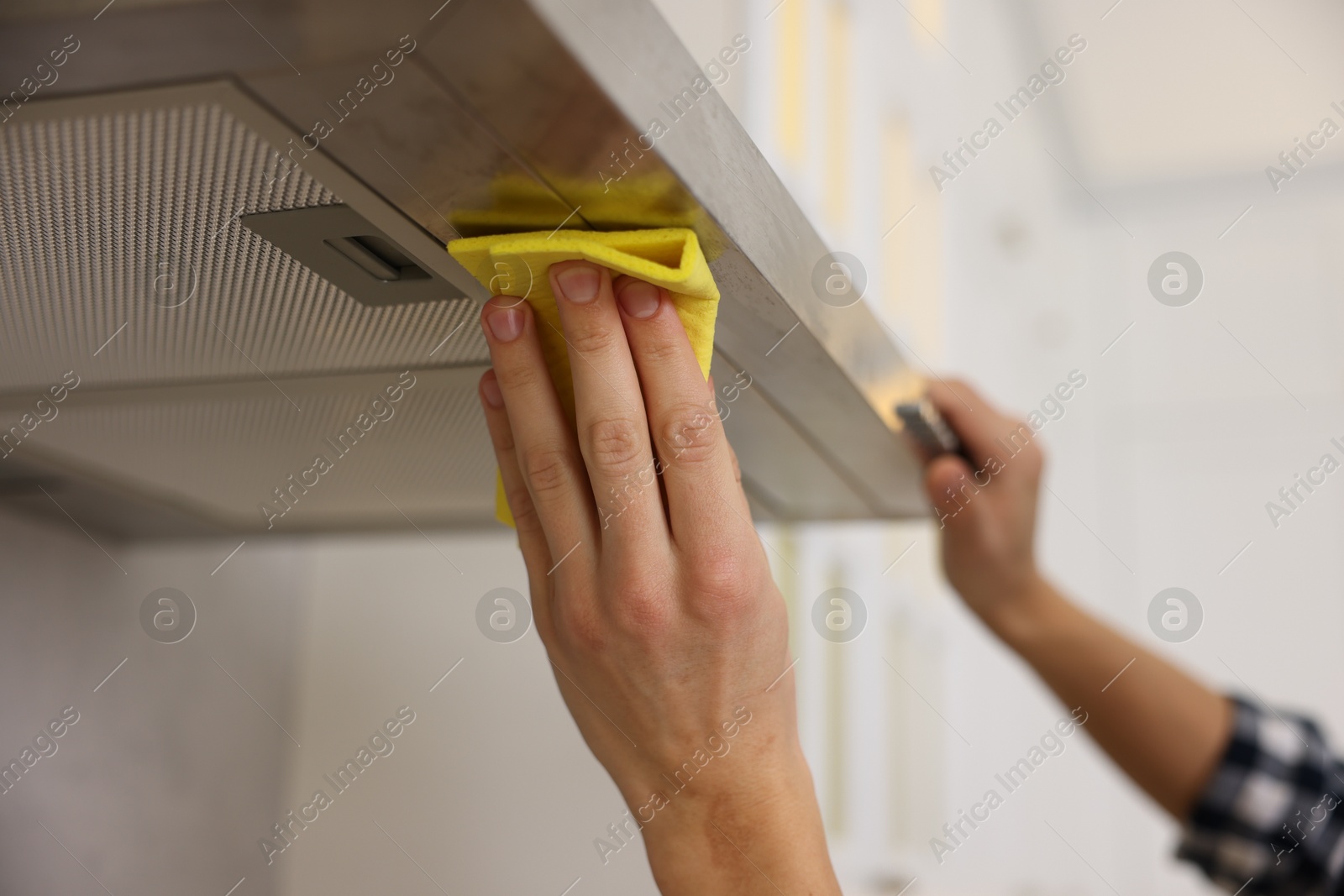 Photo of Man cleaning kitchen hood with rag indoors, closeup