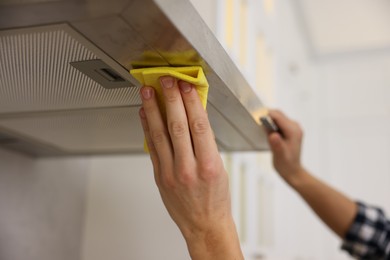 Man cleaning kitchen hood with rag indoors, closeup