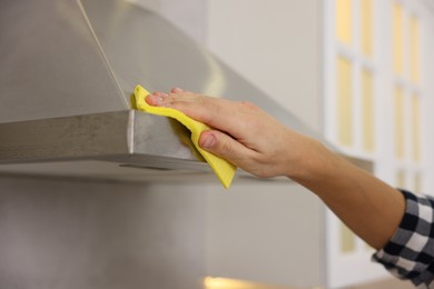 Man cleaning kitchen hood with rag indoors, closeup