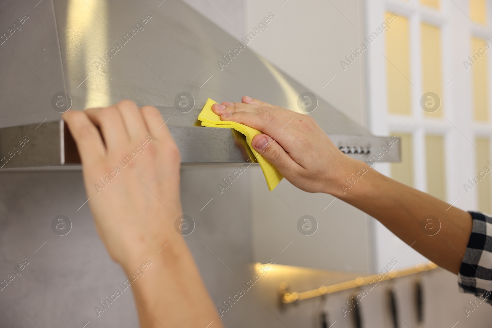 Photo of Man cleaning kitchen hood with rag indoors, closeup