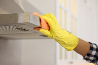 Photo of Man cleaning kitchen hood with rag indoors, closeup