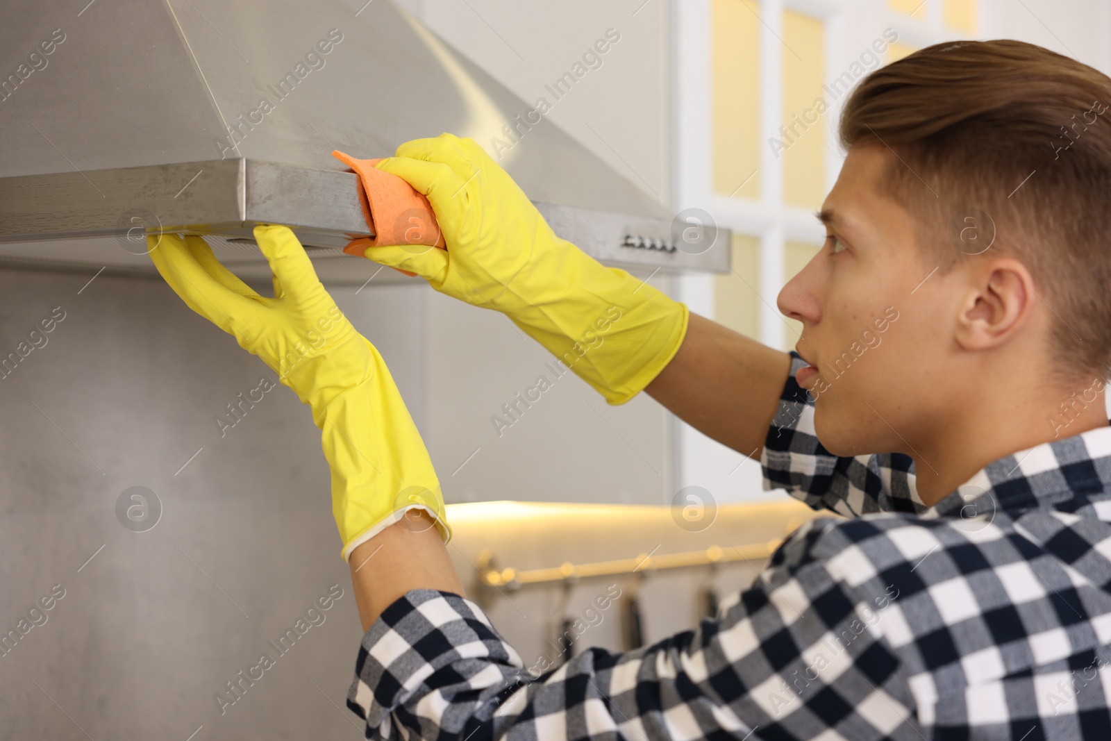 Photo of Man cleaning kitchen hood with rag at home