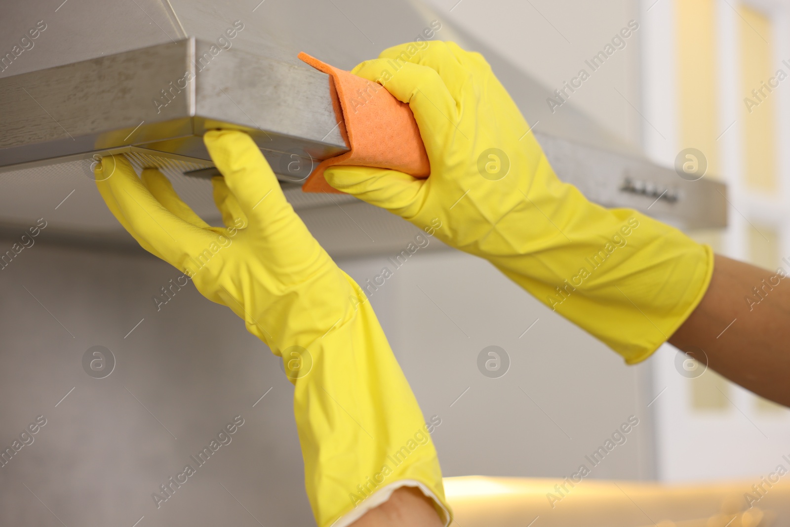 Photo of Man cleaning kitchen hood with rag indoors, closeup