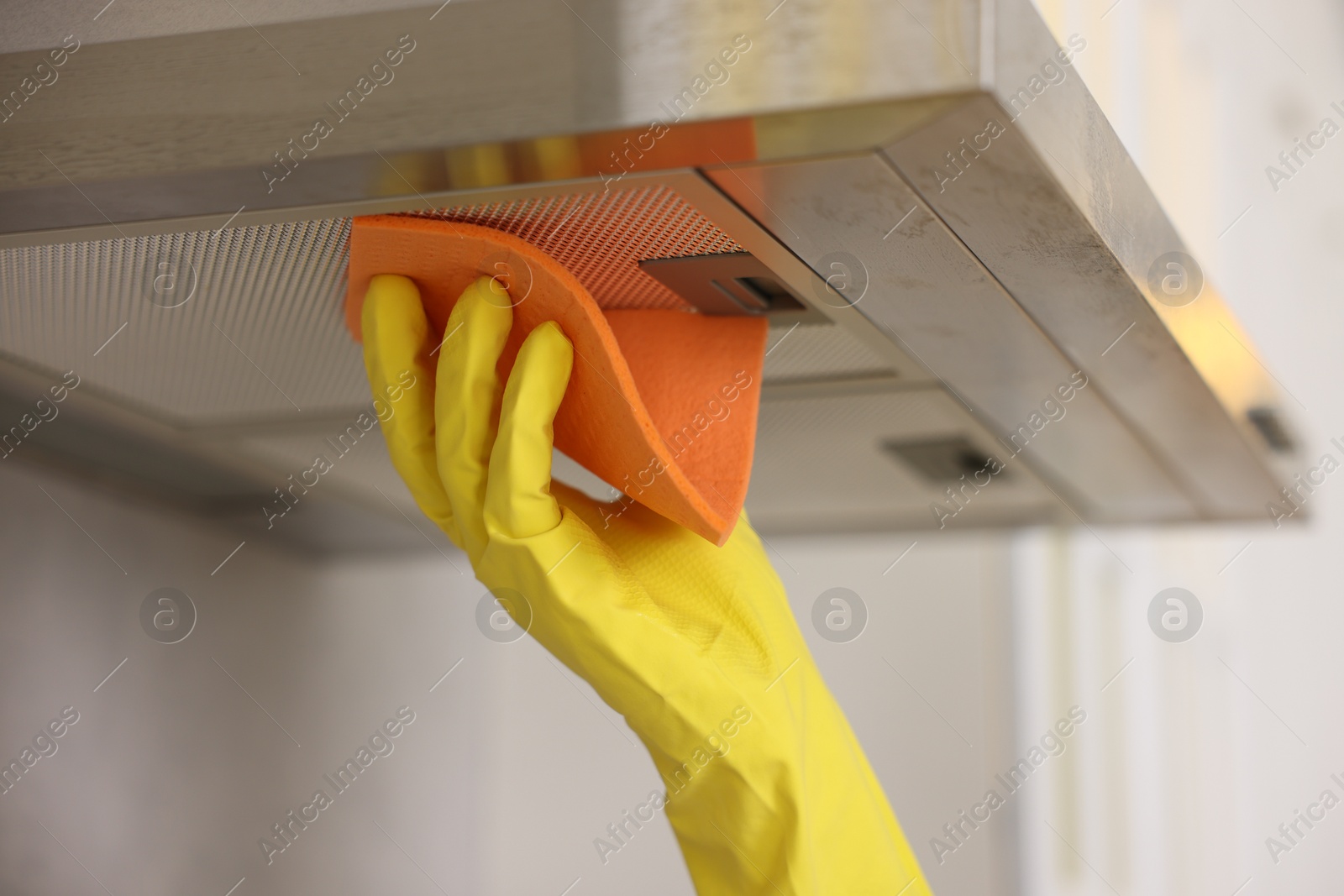 Photo of Man cleaning kitchen hood with rag indoors, closeup