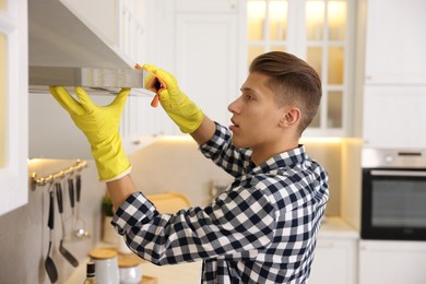 Photo of Man cleaning kitchen hood with rag at home