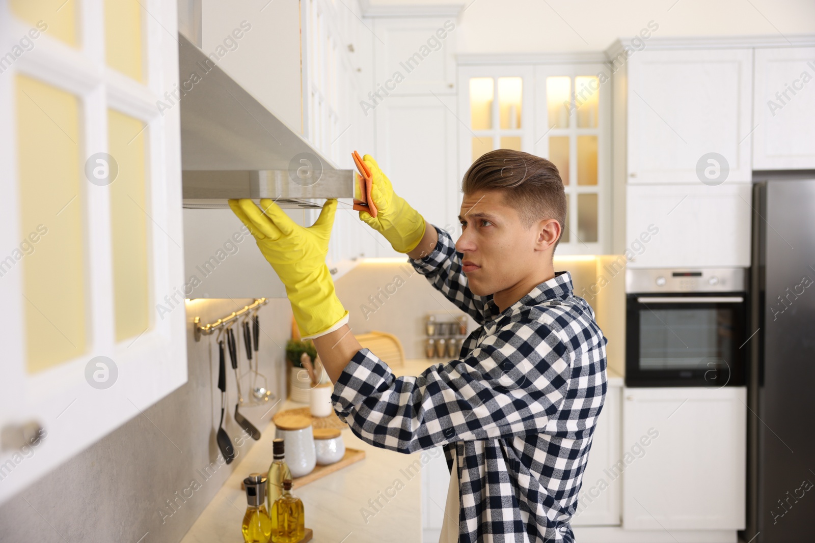 Photo of Man cleaning kitchen hood with rag at home