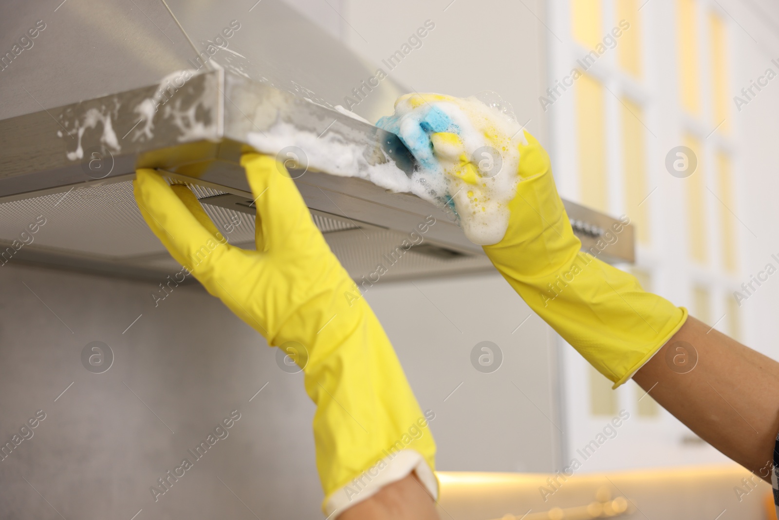 Photo of Man cleaning kitchen hood with sponge at home, closeup