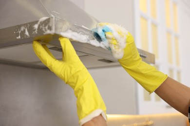 Photo of Man cleaning kitchen hood with sponge at home, closeup