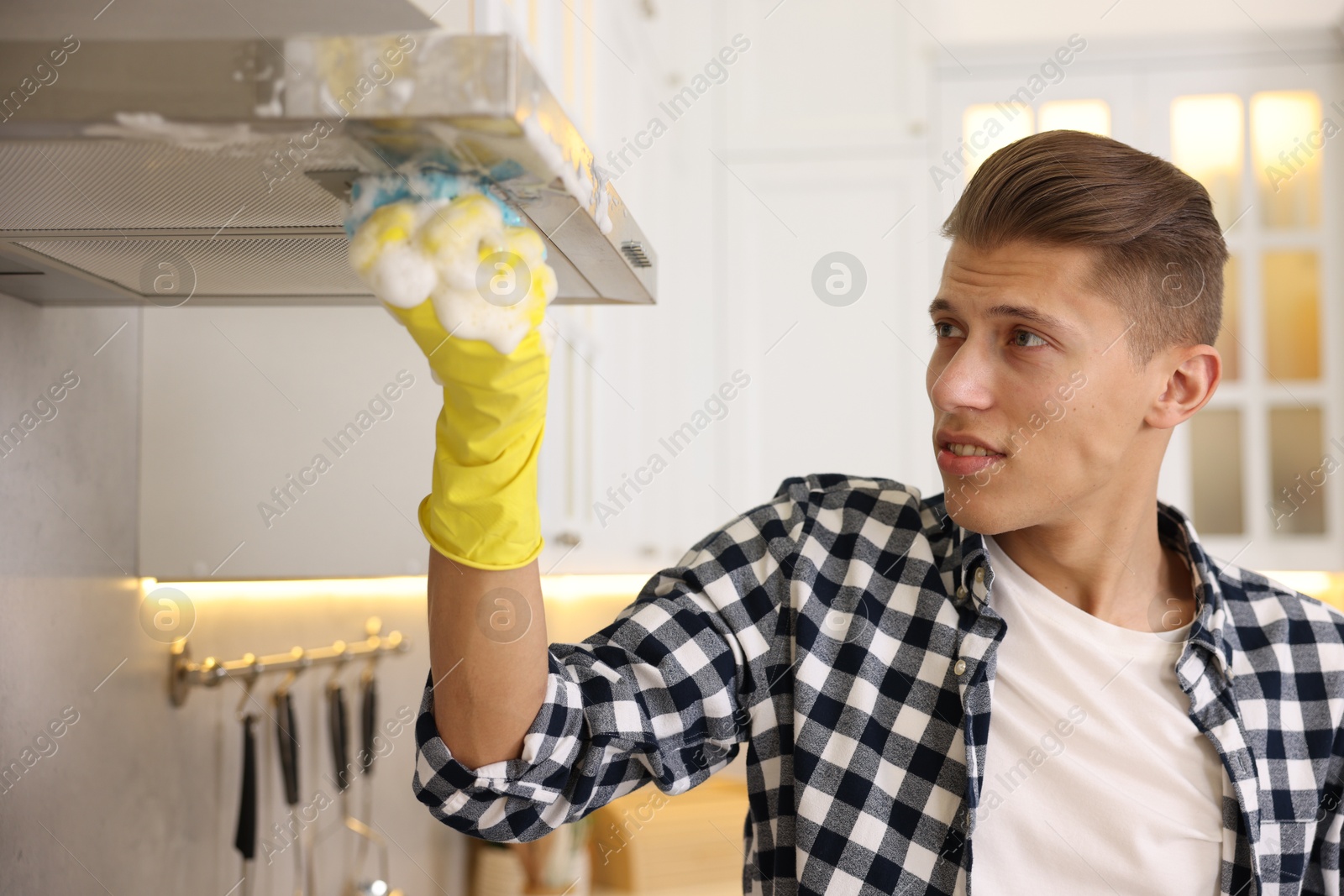 Photo of Man cleaning kitchen hood with sponge at home