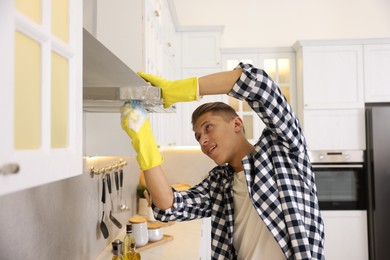 Man cleaning kitchen hood with sponge at home