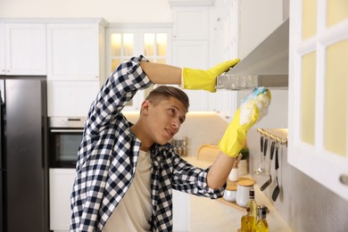 Photo of Man cleaning kitchen hood with sponge at home