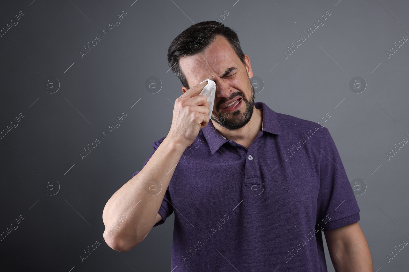 Photo of Sad man with paper tissue crying on grey background, space for text