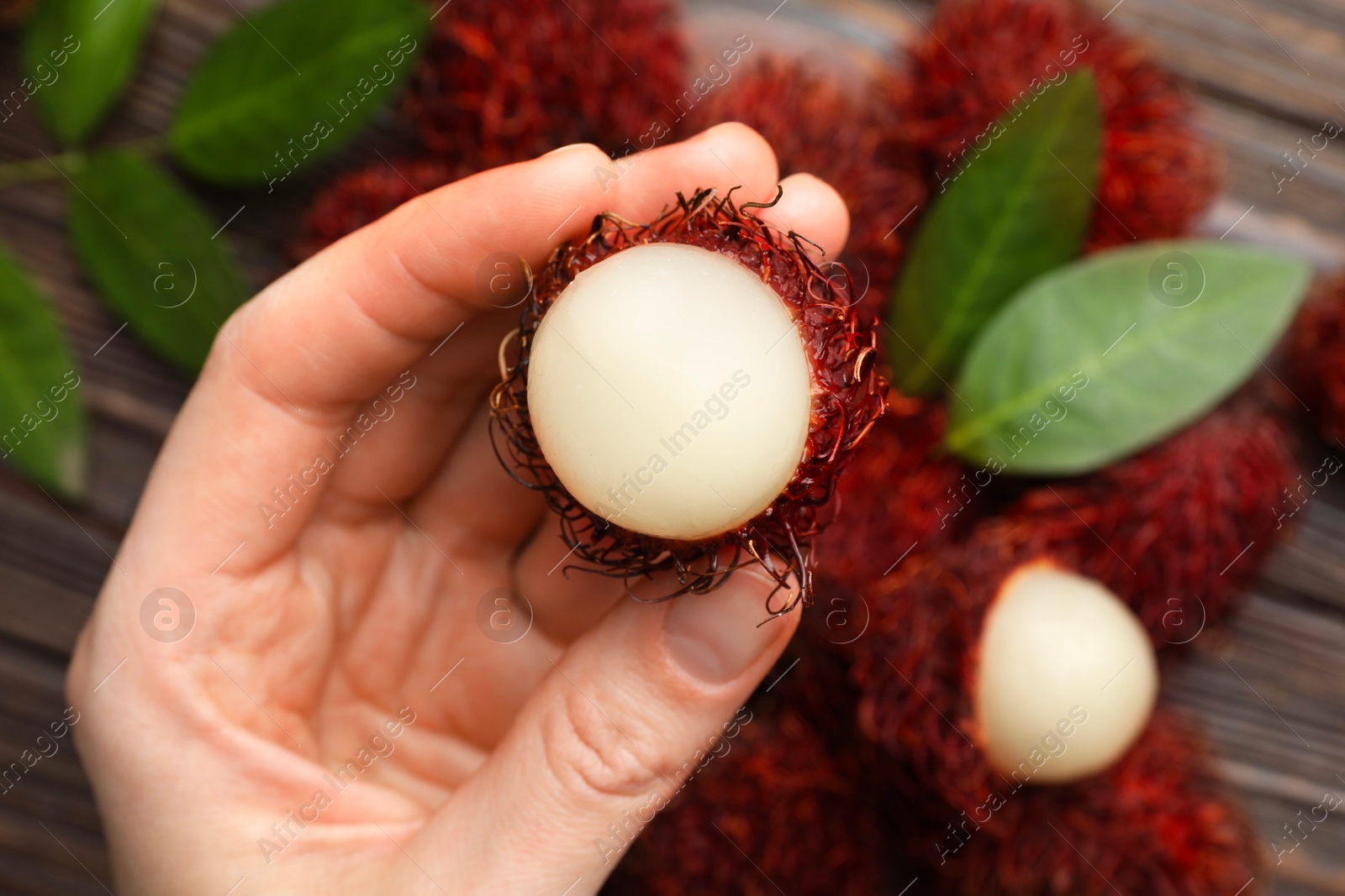 Photo of Woman with ripe rambutan at table, above view