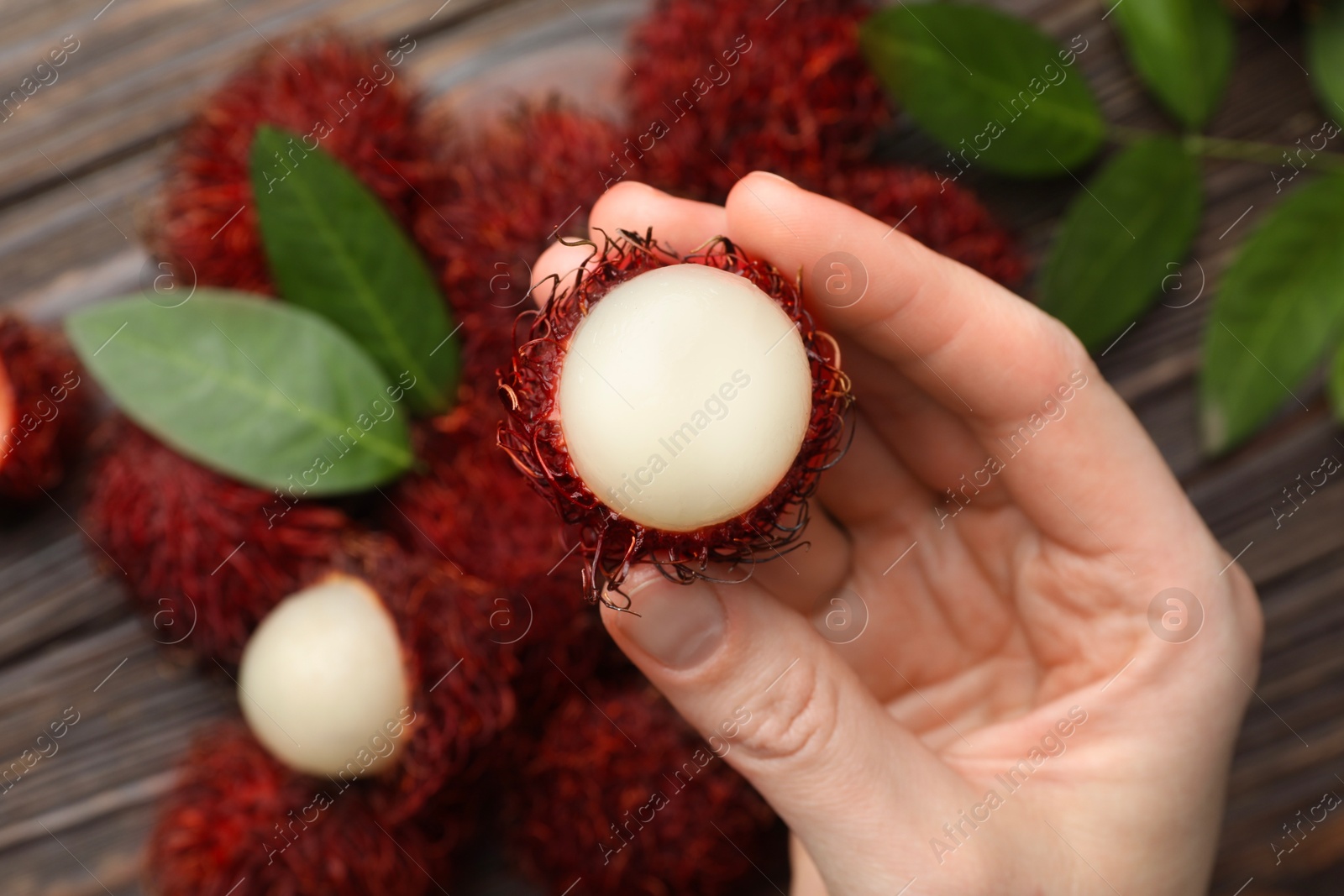 Photo of Woman with ripe rambutan at table, above view