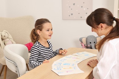 Photo of Speech therapist working with little girl at table in autism treatment center