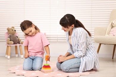 Photo of Autism therapy. Psychologist and little girl playing with educational toy in mental health center