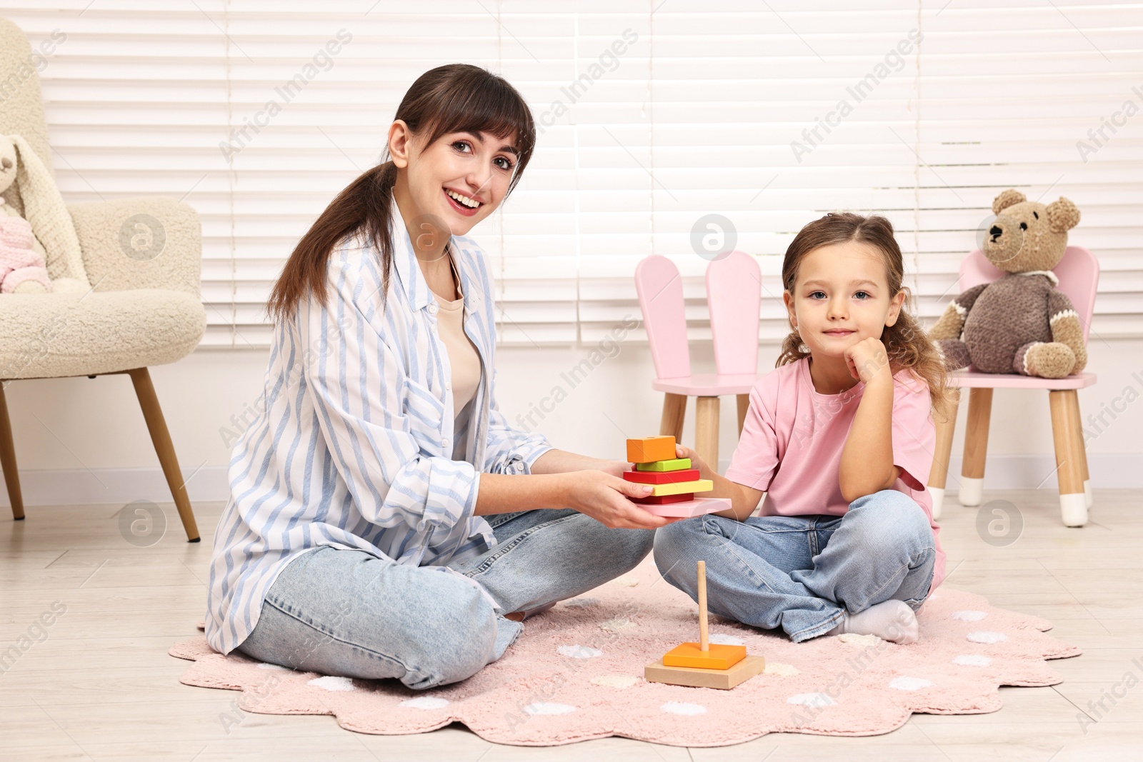 Photo of Autism therapy. Smiling psychologist and little girl playing with educational toy in mental health center