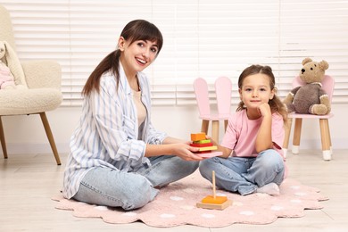 Photo of Autism therapy. Smiling psychologist and little girl playing with educational toy in mental health center